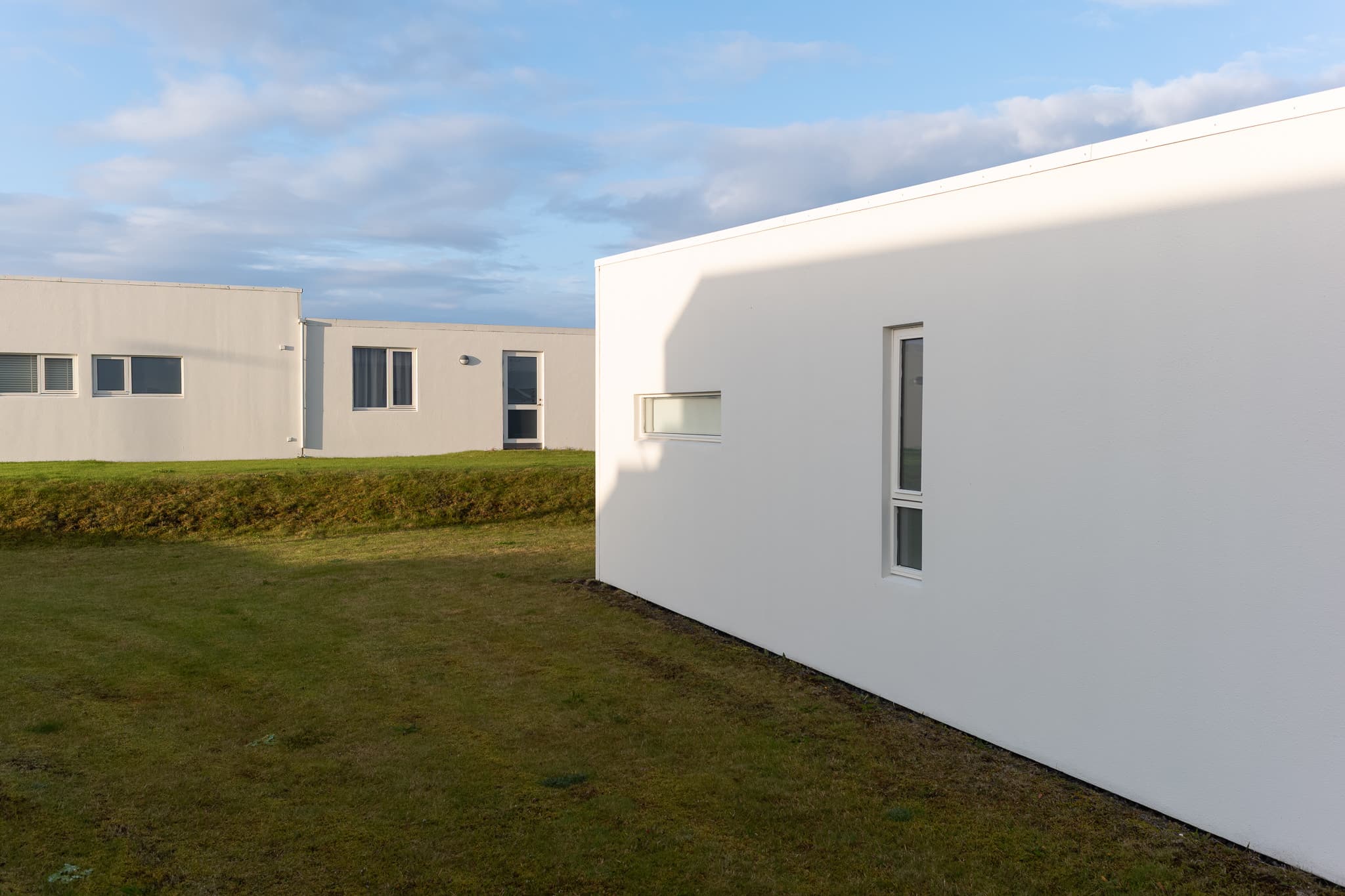 Neubau in Njarðvík Weiße Wand eines Neubaus und Rasenfläche in Njarðvík