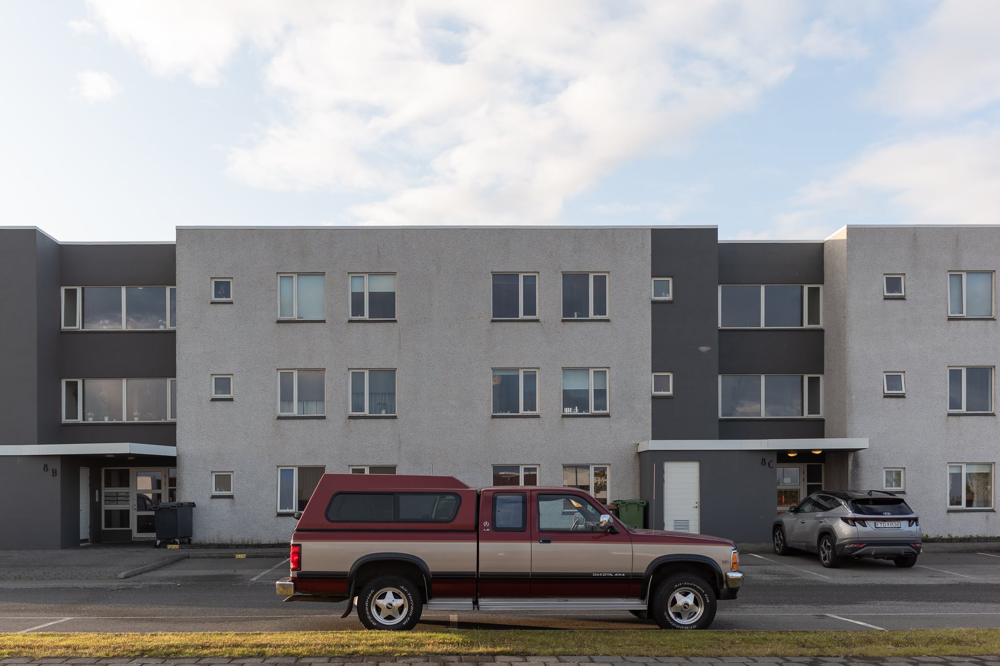 Mehrfamilienhaus in Njarðvík Graues Mehrfamilienhaus mit rotem Pick-up davor in Njarðvík