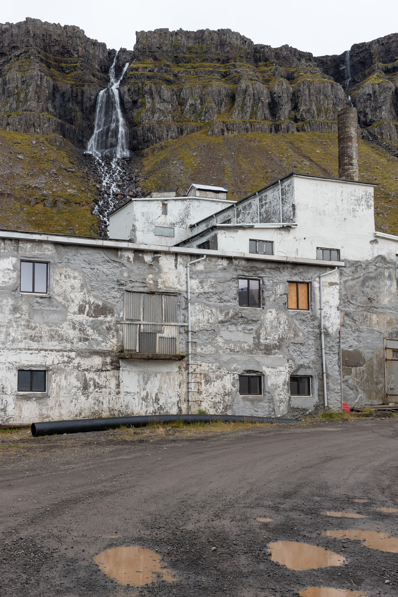 Heringsfabrik Djúpavík Heringsfabrik mit Wasserfall im Hintergrund in Djúpavík